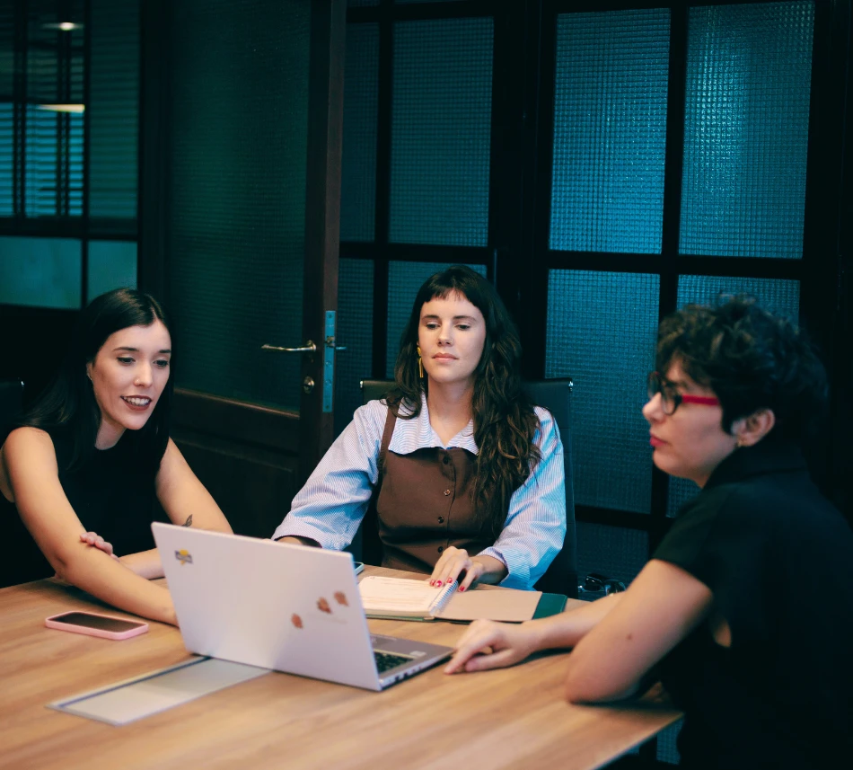 El equipo de Proyecto SHE en una reunión de trabajo alrededor de una mesa, con una notebook abierta