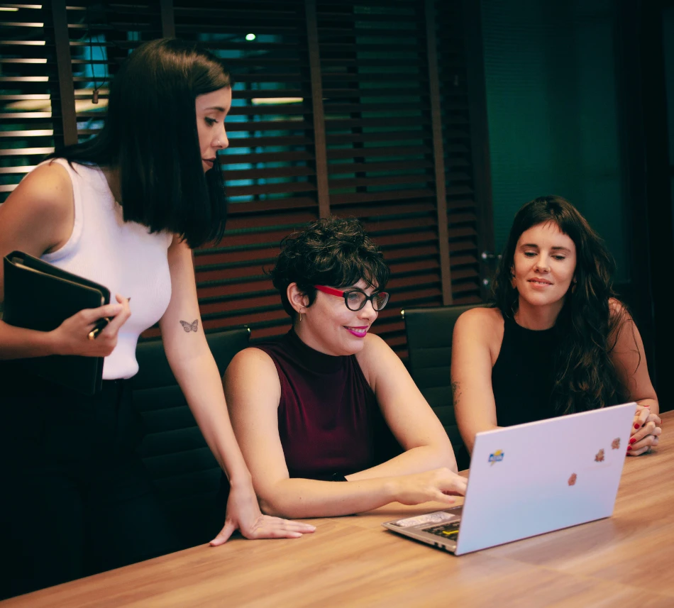 Las socias de Proyecto SHE revisando una estrategia en la notebook durante una reunión